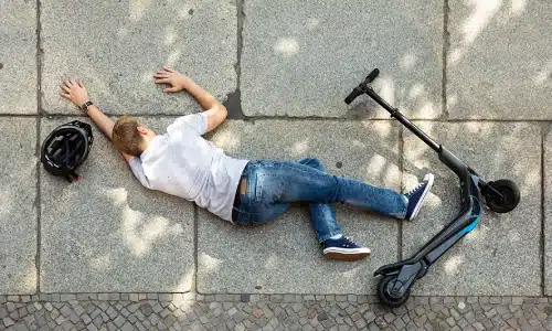 A photo of a man lying on the ground after falling from an e-scooter.