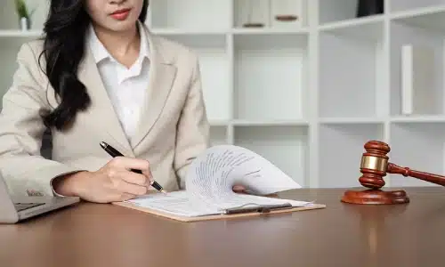 A train accident lawyer serving Long Island is holding a page from a document open to sign while sitting in a law office