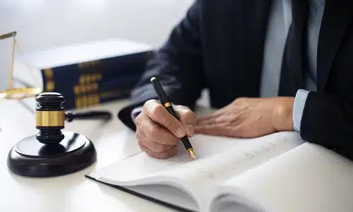 A truck accident lawyer serving long island is writing down notes on a notebook while sitting at an office desk