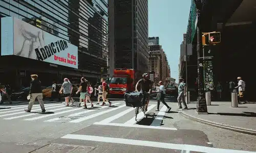 A marked pedestrian crosswalk on a busy city street with heavy foot and vehicle traffic in Manhattan.
