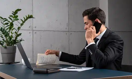 A rideshare accident lawyer serving Manhattan reviews case notes while speaking with a client on the phone.