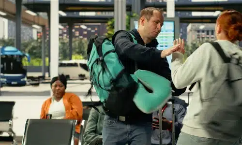 Two backpacking travelers colliding with each other in a crowded airport lobby.