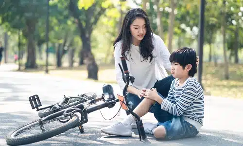 A mother checks on her child after the child falls from a bicycle during a ride.