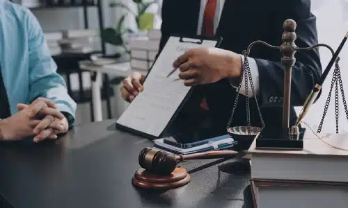 A subway accident lawyer serving Suffolk County discusses a case with a colleague while pointing to a document with a pen.